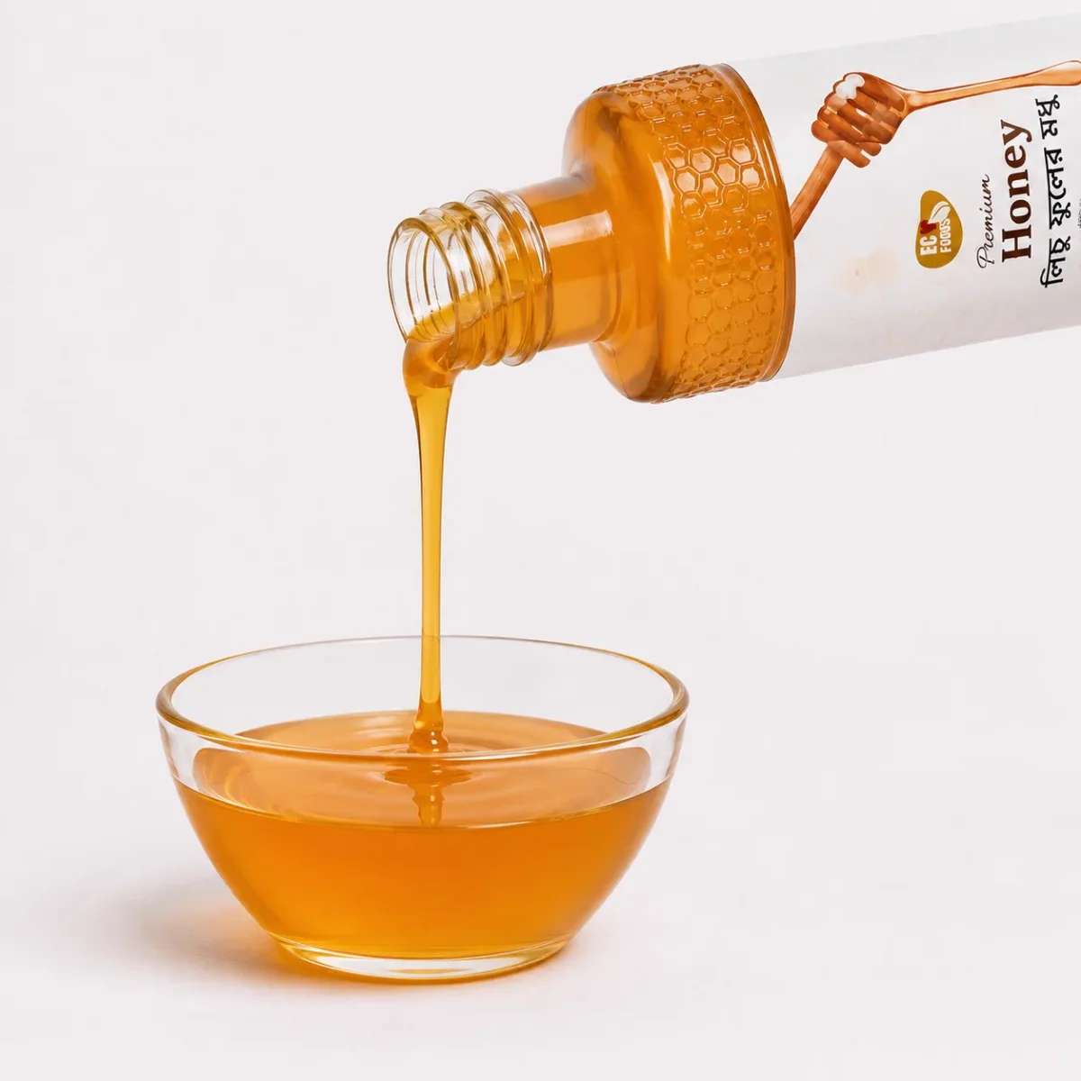 Lychee Flower Honey bottle pouring into a glass bowl - Eco Foods